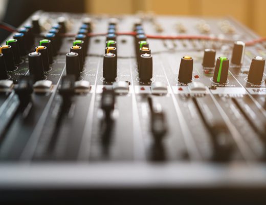 A black and white electronic instrument with green and yellow buttons. The instrument is a mixer and has a black and white color scheme